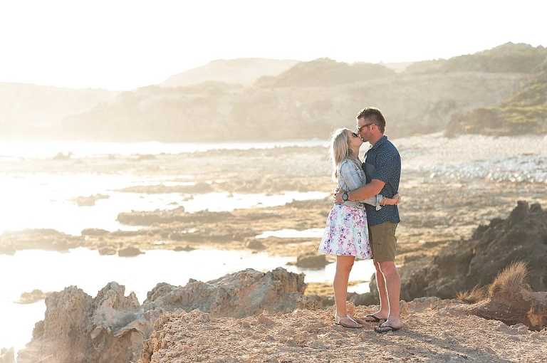 Couple kissing during engagement session on beautiful beach