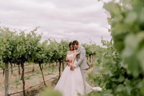 Bride and groom hugging in vineyard