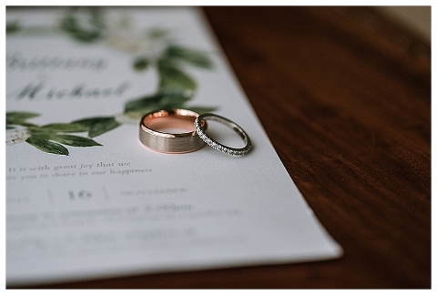Rose gold and platinum wedding rings on invitation